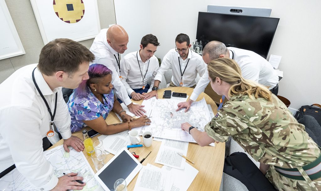 Reservist helping employees from an organisation team during the 3MI Intelligence Challenge
