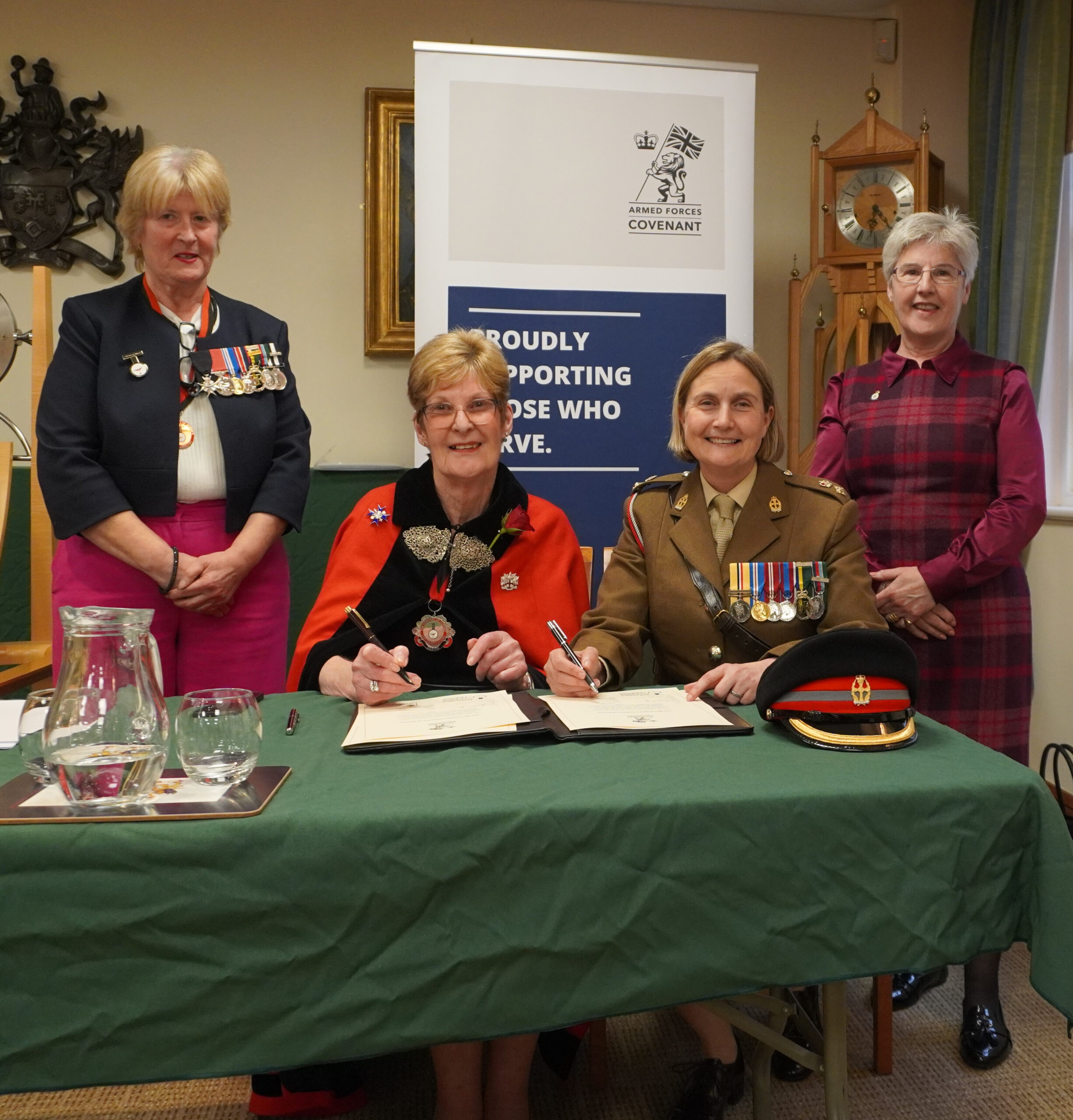 Four women posing for a signature on the Armed Forces Covenant document