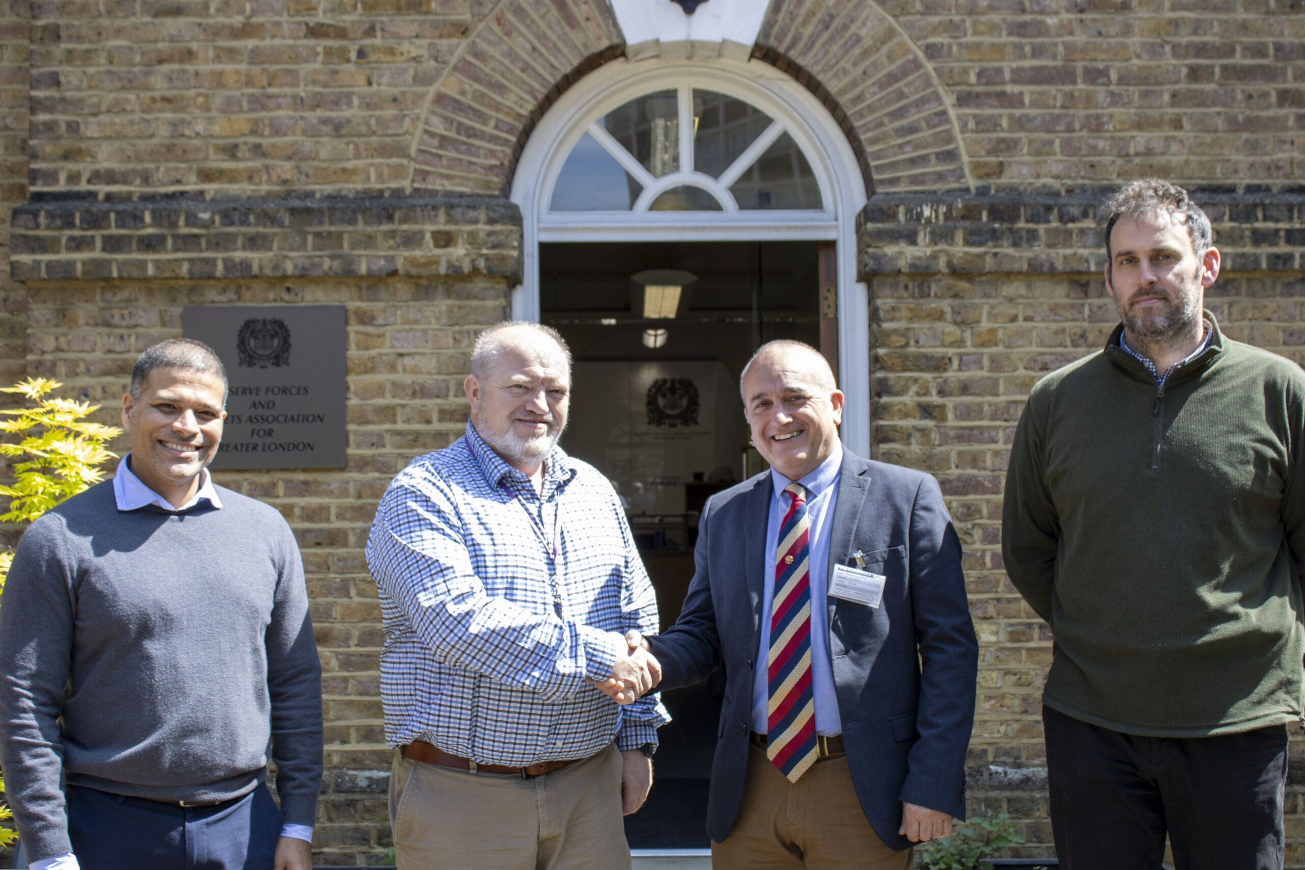 Two men shaking hands in front of a the GL RFCA building